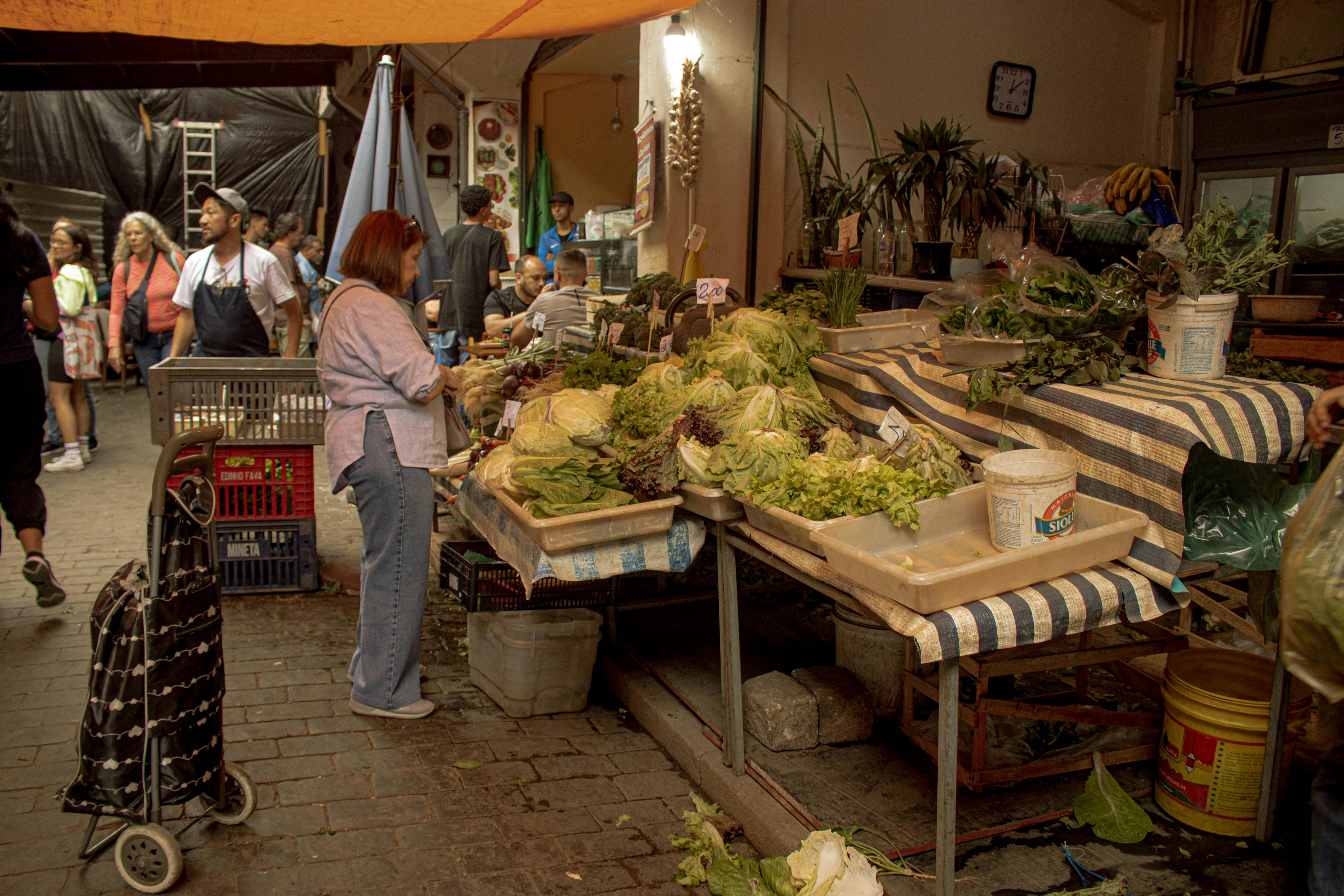 Marché de plein air animé avec étals de produits frais, clients et commerçants locaux