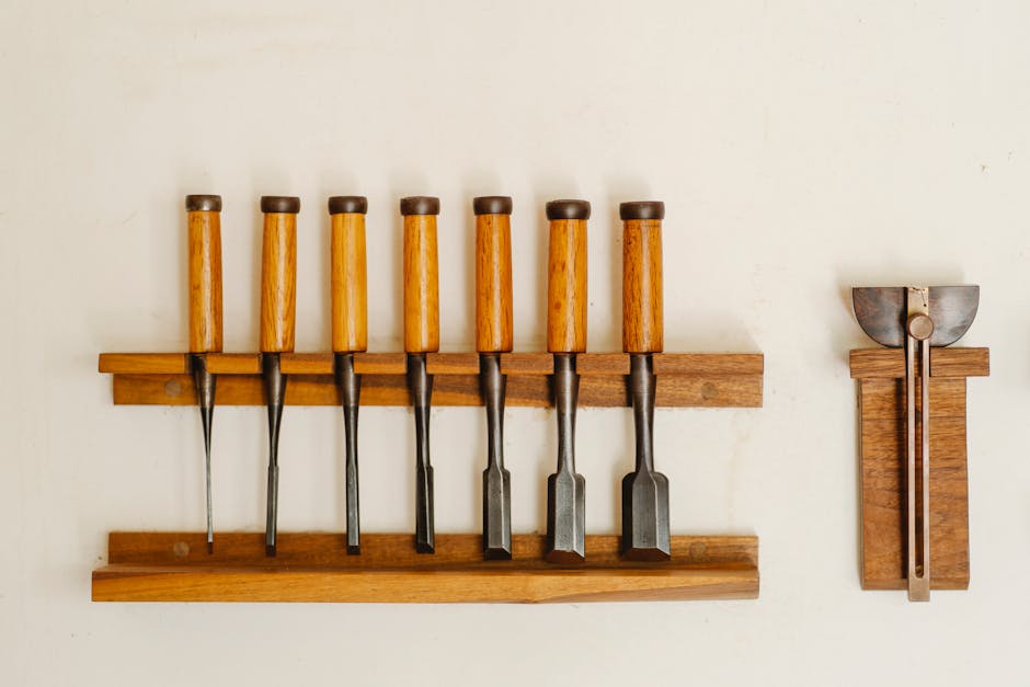 Collection de ciseaux à métal avec manches en bois et outils de découpe pour le travail du bois disposés sur une étagère contre un mur blanc dans un atelier