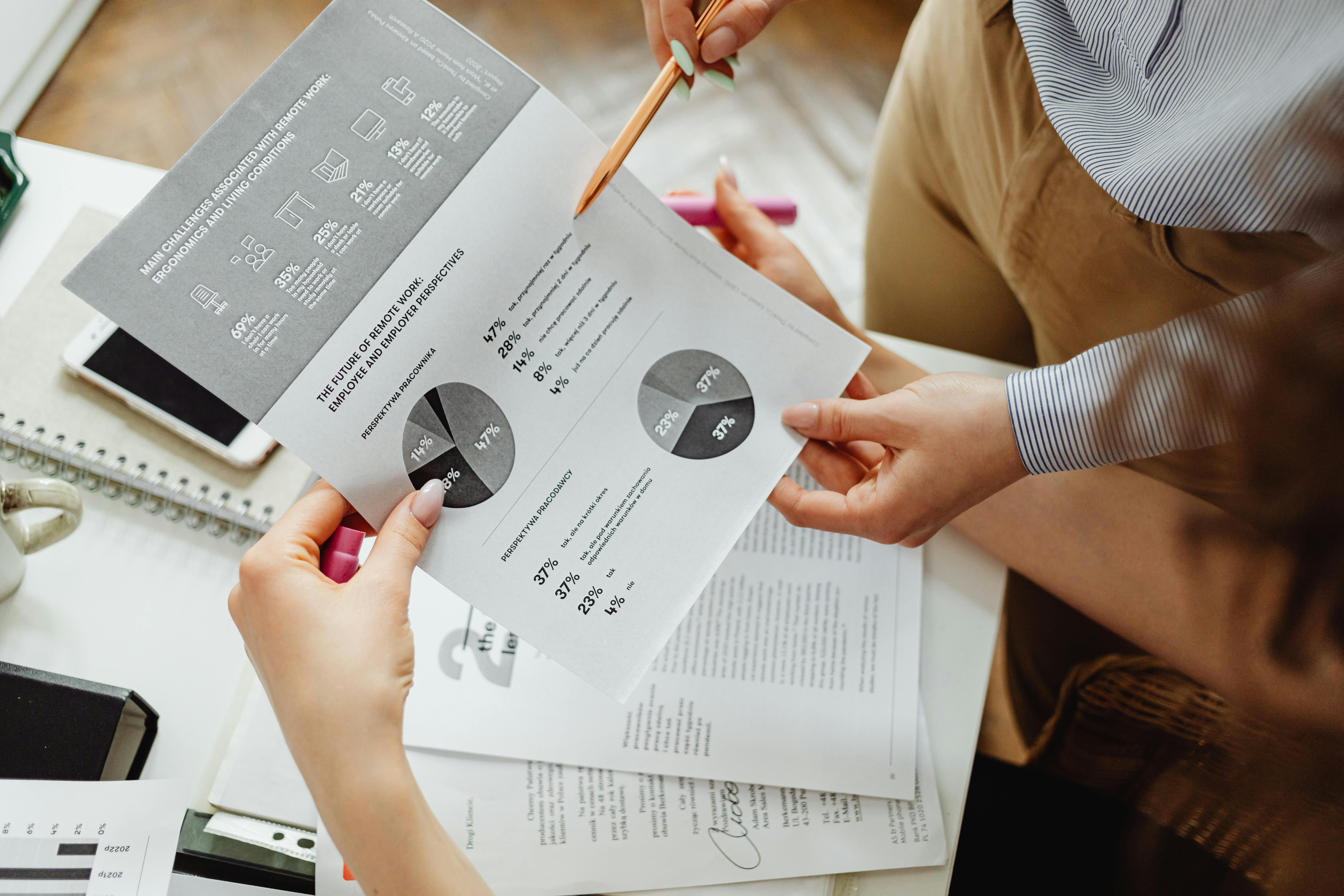 Réunion autour d'un bureau avec documents, un ordinateur portable et un graphique circulaire (camembert) montrant l'analyse de données et la collaboration pour interpréter des retours clients.