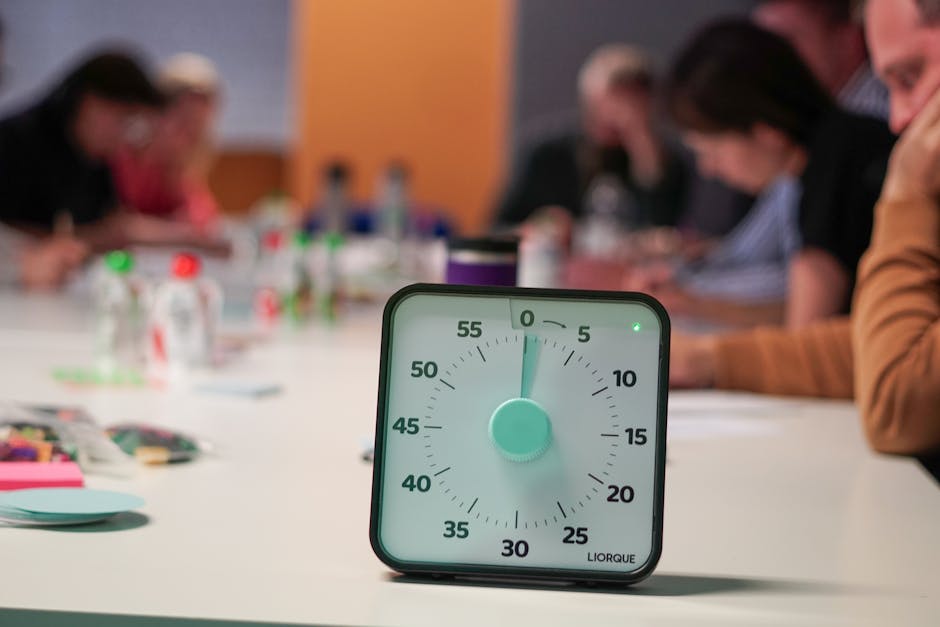 Minuterie sur une table avec des personnes floues en réunion, symbolisant l'importance du timing