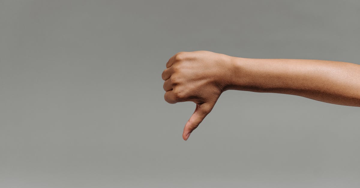 Main effectuant un geste de désapprobation sur fond gris, illustrant une réaction négative à un avis client