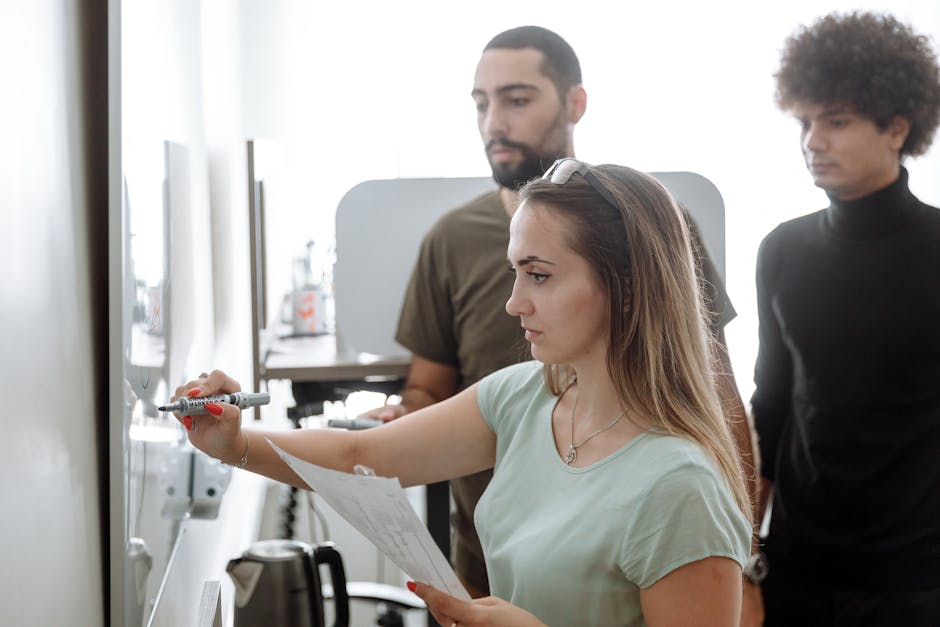 Trois jeunes professionnels en train de brainstormer autour d'un tableau blanc dans un bureau moderne.