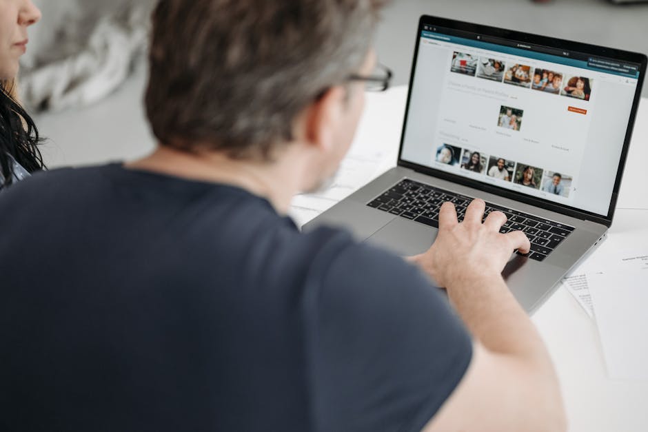 Adult man browsing online profiles on a laptop, immersed in digital browsing indoors.