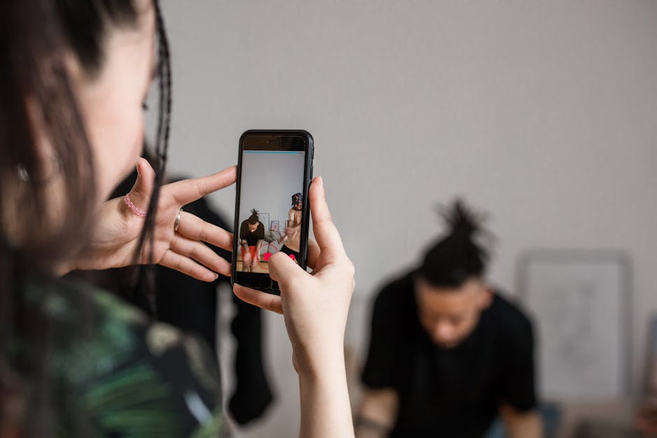 Gros plan d'une personne en train d'enregistrer une vidéo avec un smartphone à l'intérieur, concentrée sur la création de contenu créatif.