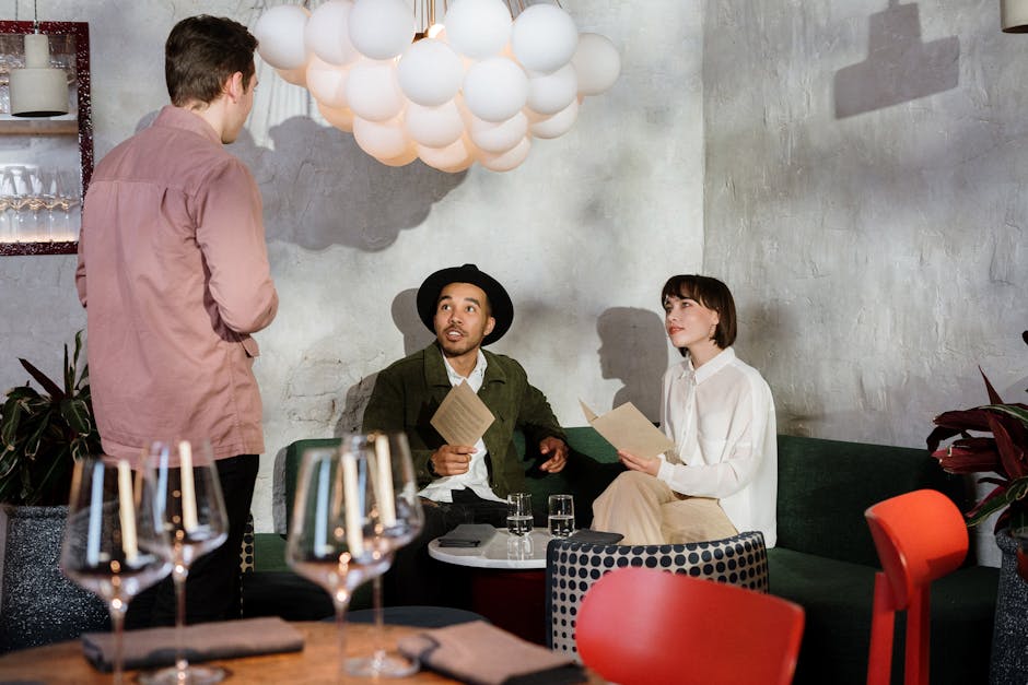 Una pareja examina un menú en un restaurante elegante, mientras habla con un camarero.
