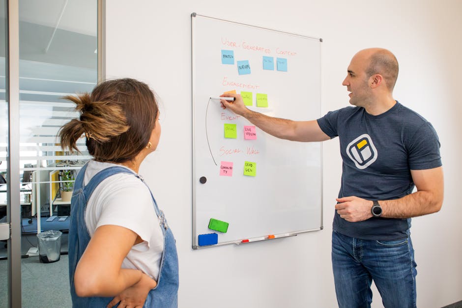 Two colleagues planning a marketing strategy in front of a whiteboard