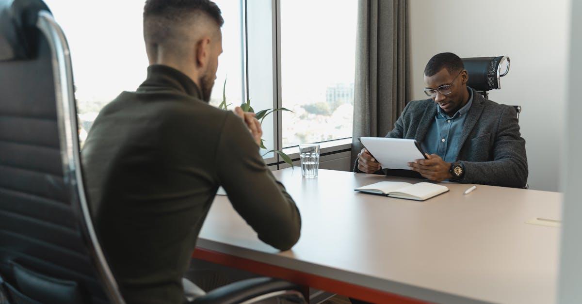 Personne en tenue professionnelle à un bureau moderne, prenant des notes dans un carnet et travaillant sur la gestion et la vérification des avis en ligne.