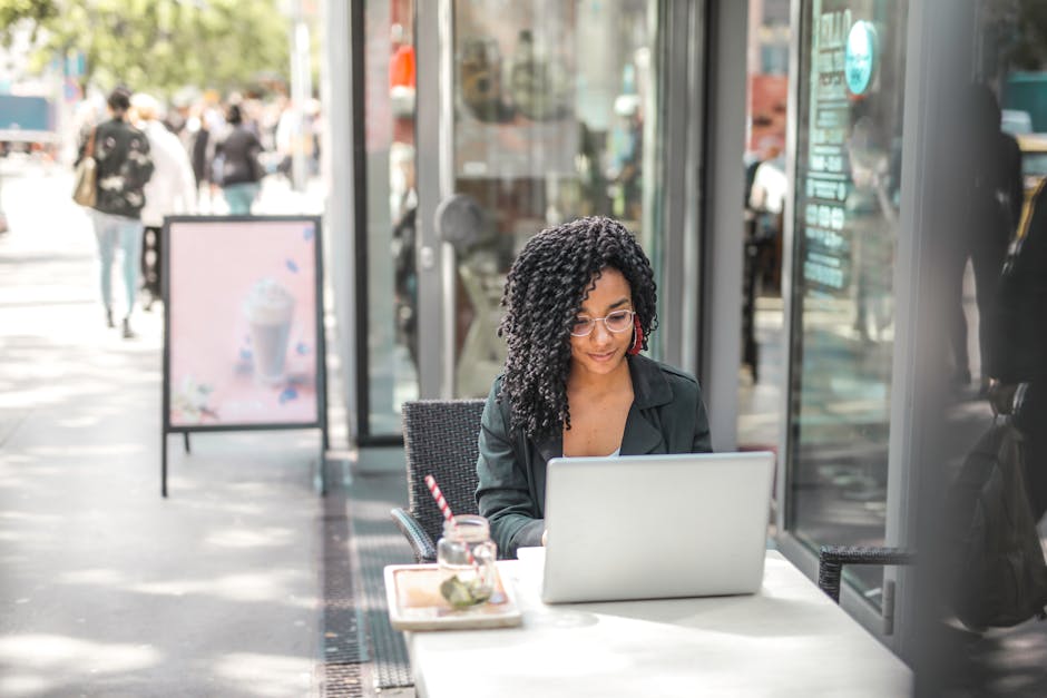 Jeune femme afro-américaine travaillant sur ordinateur portable dans un café, illustrant la consultation d'avis clients