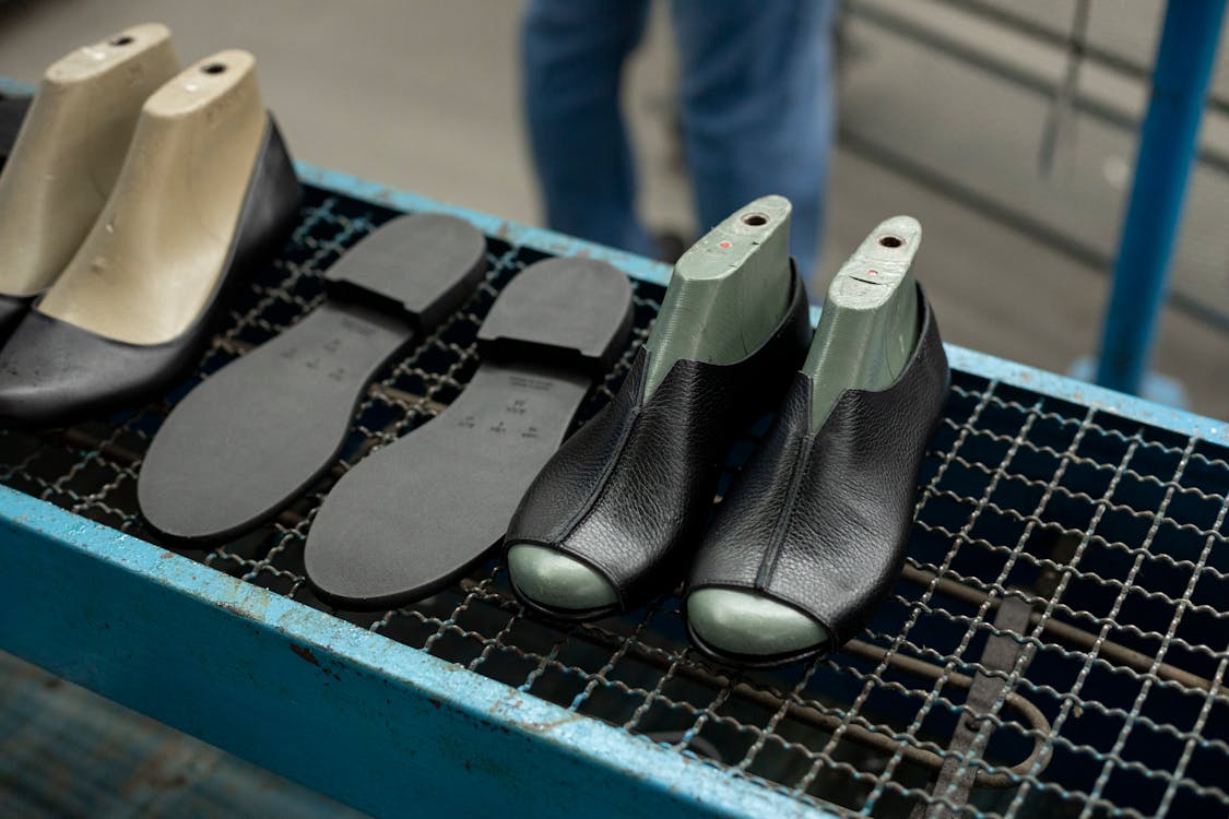 Atelier artisanal de fabrication de chaussures avec un artisan effectuant un contrôle de qualité des pièces et de l'assemblage, établissant un processus de vérification et d'assurance qualité