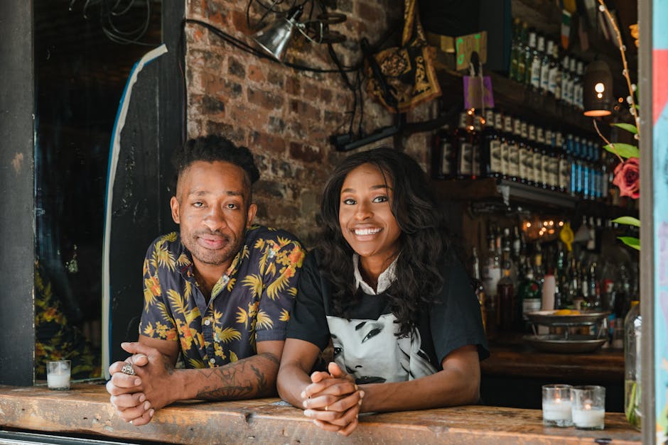 Un couple souriant en tenue décontractée au comptoir d'un café chaleureux, entouré d'une décoration conviviale.