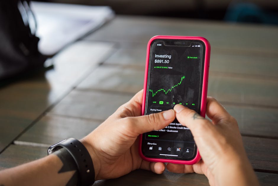 Personne tenant un smartphone affichant une application boursière avec des analyses et cours des actions.