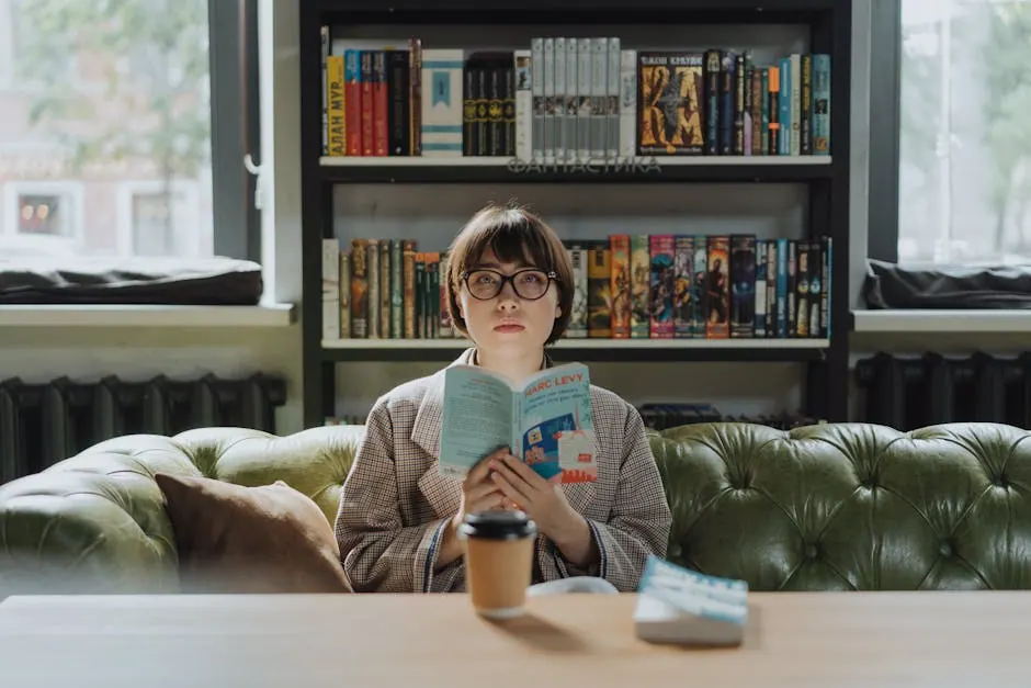 A young woman enjoys a moment of reading in a cozy library, a book in hand and a coffee on the table.