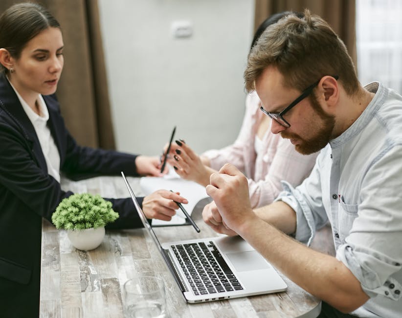 Trois professionnels discutant de nouvelles idées autour d'un ordinateur portable dans un cadre de bureau collaboratif.