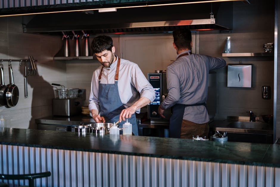 Deux chefs travaillant dans une cuisine ouverte, préparant des plats dans un restaurant moderne.