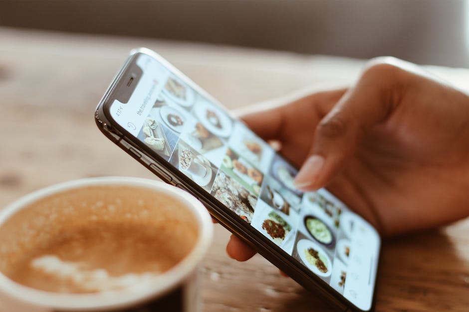 Person browsing social media with a smartphone next to a cup of coffee