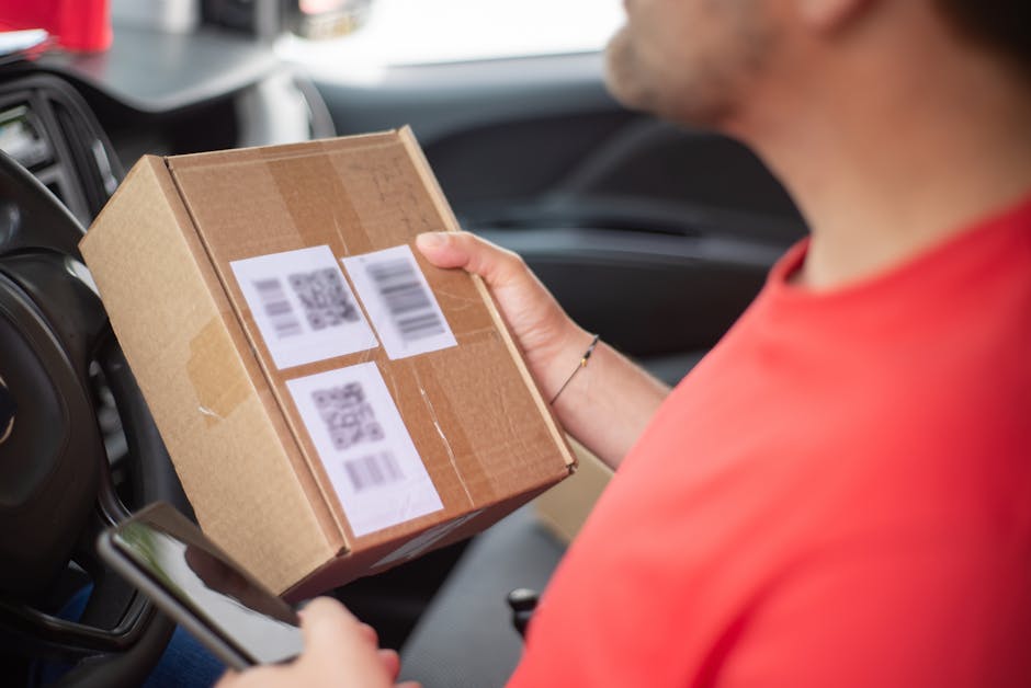 Gros plan sur une personne tenant un colis avec des QR codes dans une voiture, mettant l'accent sur la livraison et la technologie.