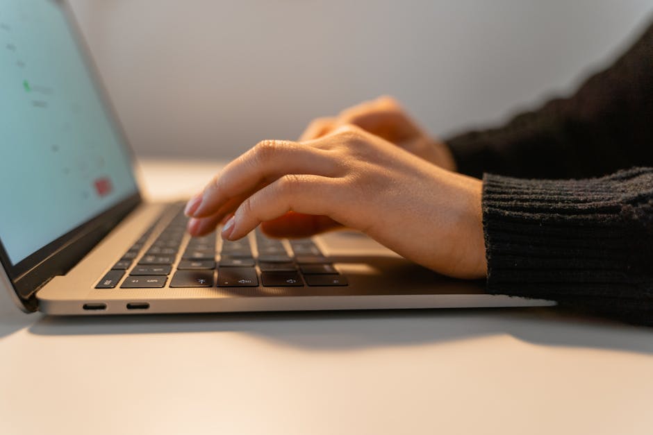 Gros plan sur des mains tapant sur un clavier d’ordinateur portable, illustrant le concept de travail à distance et de technologie.
