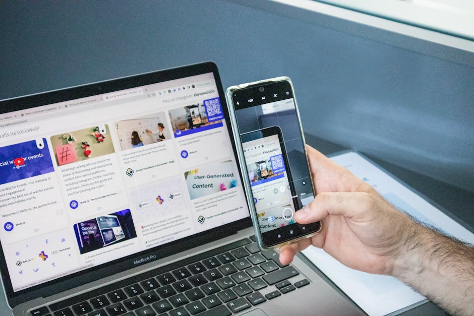 Gros plan d'un smartphone capturant un écran d'ordinateur portable, symbolisant l'intégration technologique.