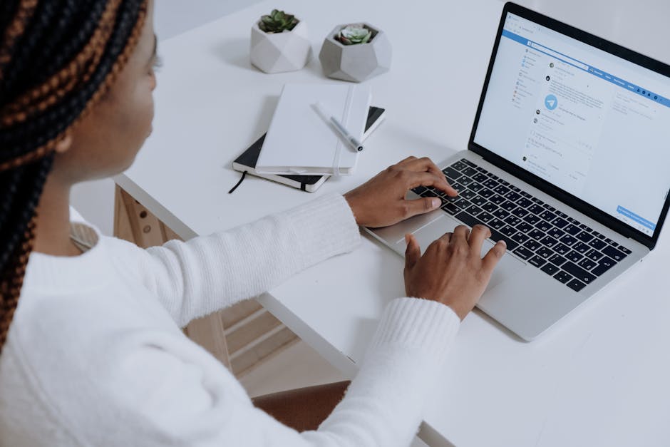 Femme consultant les réseaux sociaux sur ordinateur dans un espace de travail moderne.