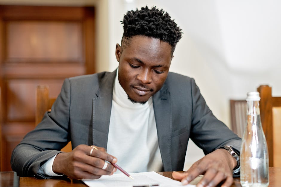 Un homme d'affaires signant des documents dans un cadre formel, concentré sur la paperasse.