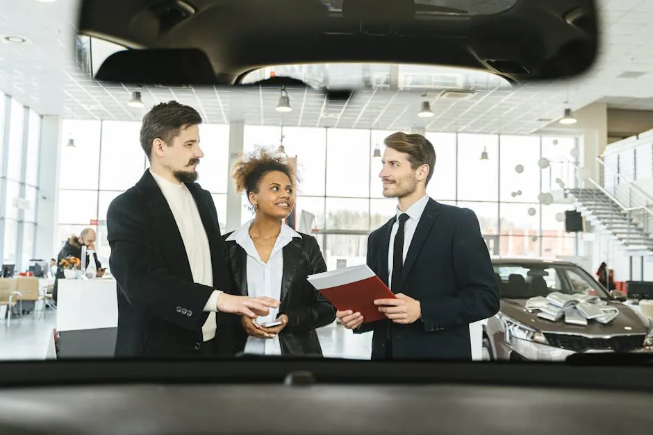 A group of three people discussing car buying options inside a dealership.