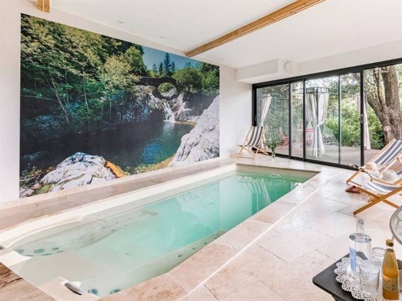 Piscine intérieure de l'hôtel, avec fresque de rivière et baies ouvertes sur le jardin